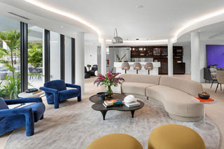 Luxury Home Staging - Modern living room with curved beige sofa, blue armchairs, and a coffee table.