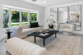 Turnkey Furniture Rental Miami. Modern living room with white furniture, black coffee table, and large mirrors.
